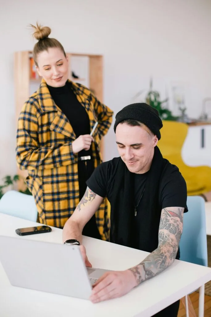 Two colleagues collaborating at a laptop in a bright modern studio office